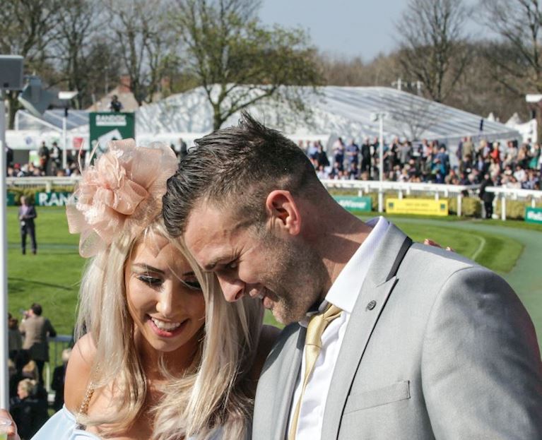 A couple standing looking over the parade ring during the grand national festival