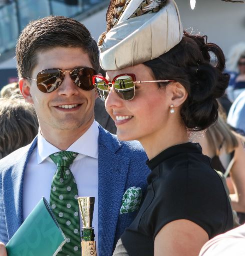 an attractive young couple watching racing during the grand national festival
