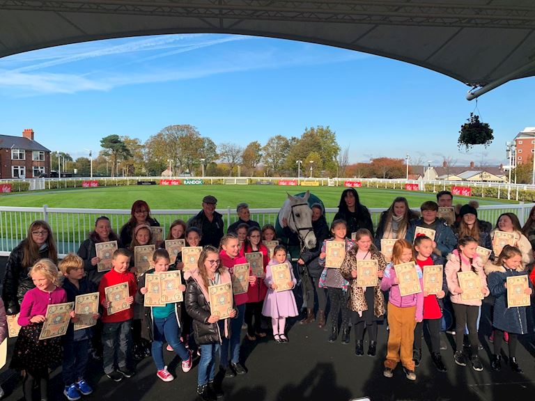 A group of school children in the Aintree Parade Ring with Grand National winning horse, Neptune Collonges.